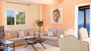 A living room with two sofas, a coffee table, a TV, and a painting on the wall. - Villa Eione-Thaleia - Lefkada Vacation (LEFKADA)