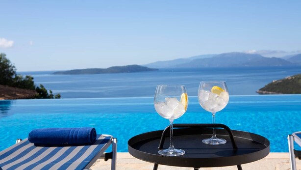 A poolside view with two glasses of a clear beverage with lemon slices, a blue towel, and a chair. - Villa Eione-Thaleia - Lefkada Vacation (LEFKADA)