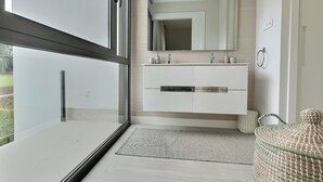 Un baño moderno con un espejo grande, muebles blancos y cabina de ducha de vidrio.