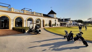 Un campo de golf con un club de campo que cuenta con ventanas arqueadas y una torre.