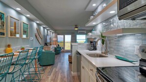 A modern kitchen with a large island, stainless steel appliances, and a view to the outside. - 2 Beachfront Condos, Pool, Tennis/Pickleball, Gulf View | Island Retreat Complex (Port Aransas)
