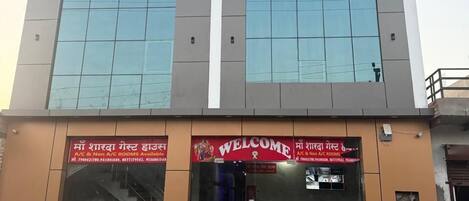 A hotel named "Hotel Sharda Palace" with a modern facade, large windows, and a welcoming entrance.