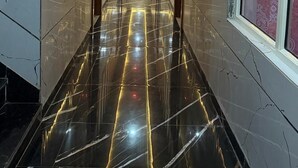 A hallway with a reflective black marble floor, wooden paneling on the walls, and a ceiling with recessed lighting. - Hotel Sharda Palace (Vrindavan)