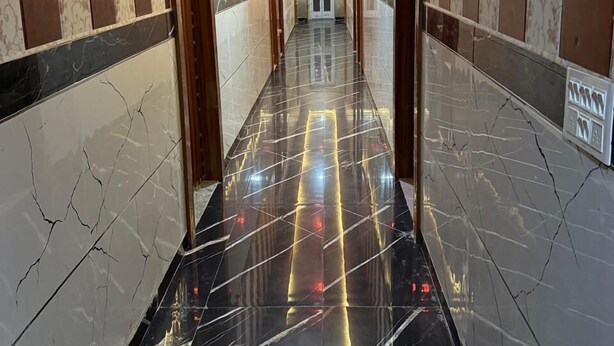 A long, narrow hallway with wooden paneling and marble flooring. - Hotel Sharda Palace (Vrindavan)