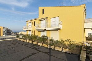 Un edificio giallo con un balcone e piante in vaso di fronte.