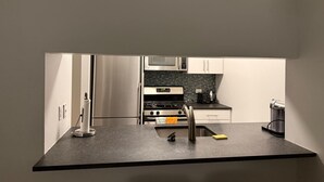 Uma cozinha moderna com bancada preta, eletrodomésticos de aço inoxidável e armários brancos.