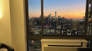 Sala de estar moderna com uma grande janela para uma vista urbana ao pôr do sol.
