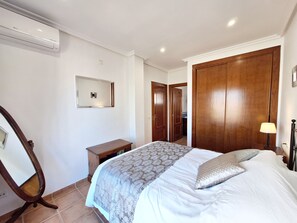 Relax in a spacious room with a large bed, wooden nightstand, and desk, perfect for working or unwinding.
