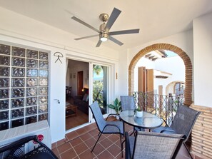 Enjoy a peaceful retreat on the balcony with a ceiling fan overhead, glass door leading to a dining area, and a comfortable seating space.