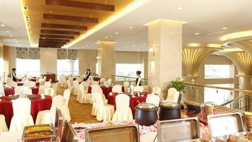 A banquet hall with round tables, white chairs, and buffet stations.