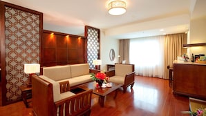 Quarto de hotel com sofá, poltronas, mesa de centro, escrivaninha e minibar.