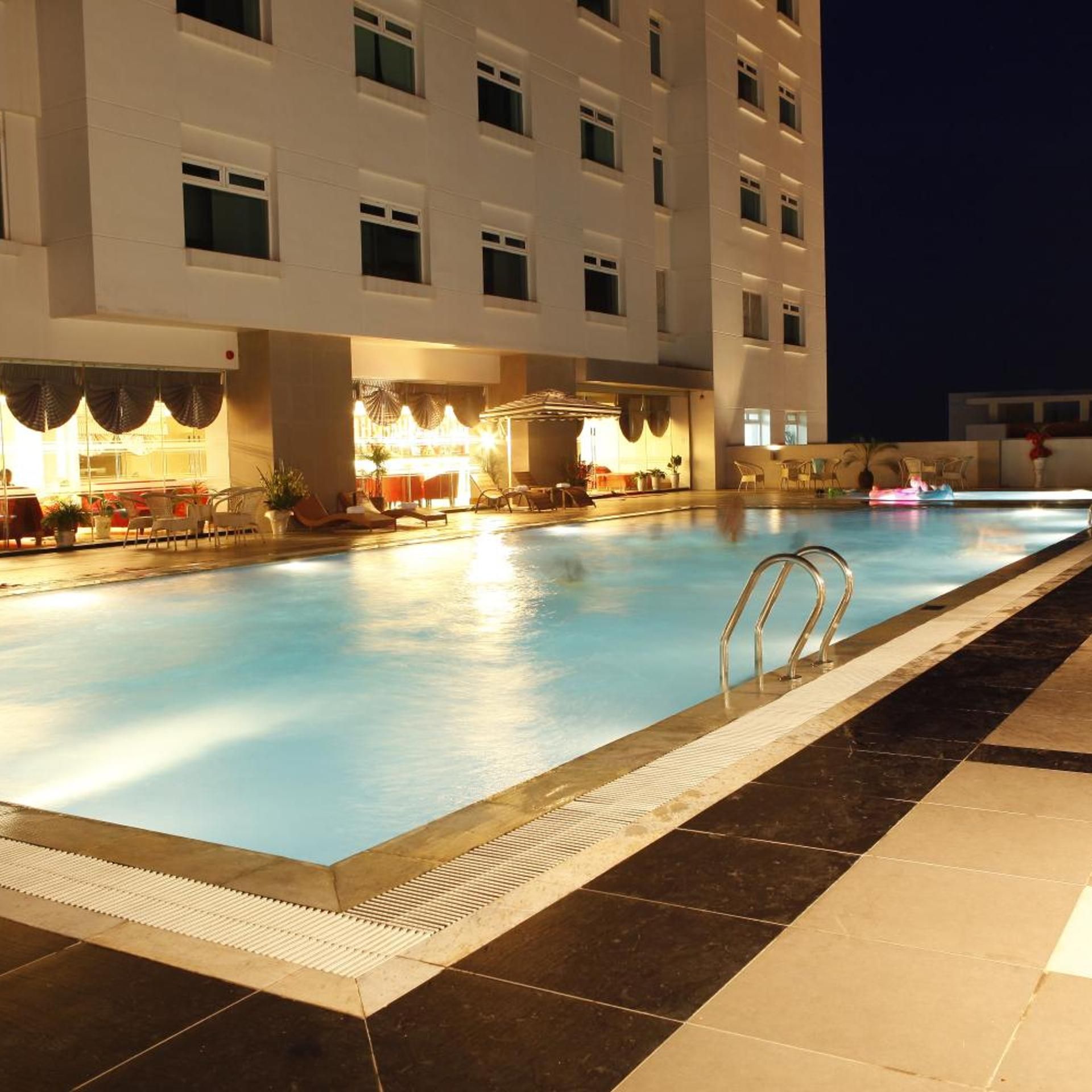 A swimming pool with a sunken seating area and a covered section with tables and chairs.