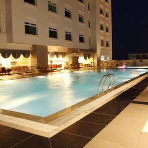 A swimming pool with a sunken seating area and a covered section with tables and chairs. - Majestic Mong Cai Hotel (Mong Cai)