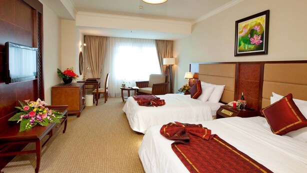 A hotel room with two beds, a desk, a chair, a television, and a painting on the wall. - Majestic Mong Cai Hotel (Mong Cai)
