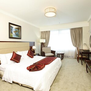 A hotel room with a large bed, a desk, a chair, a lamp, and a painting on the wall. - Majestic Mong Cai Hotel (Mong Cai)