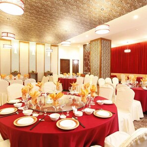A banquet hall with round tables set for dining, white chairs, and decorative centerpieces. - Majestic Mong Cai Hotel (Mong Cai)