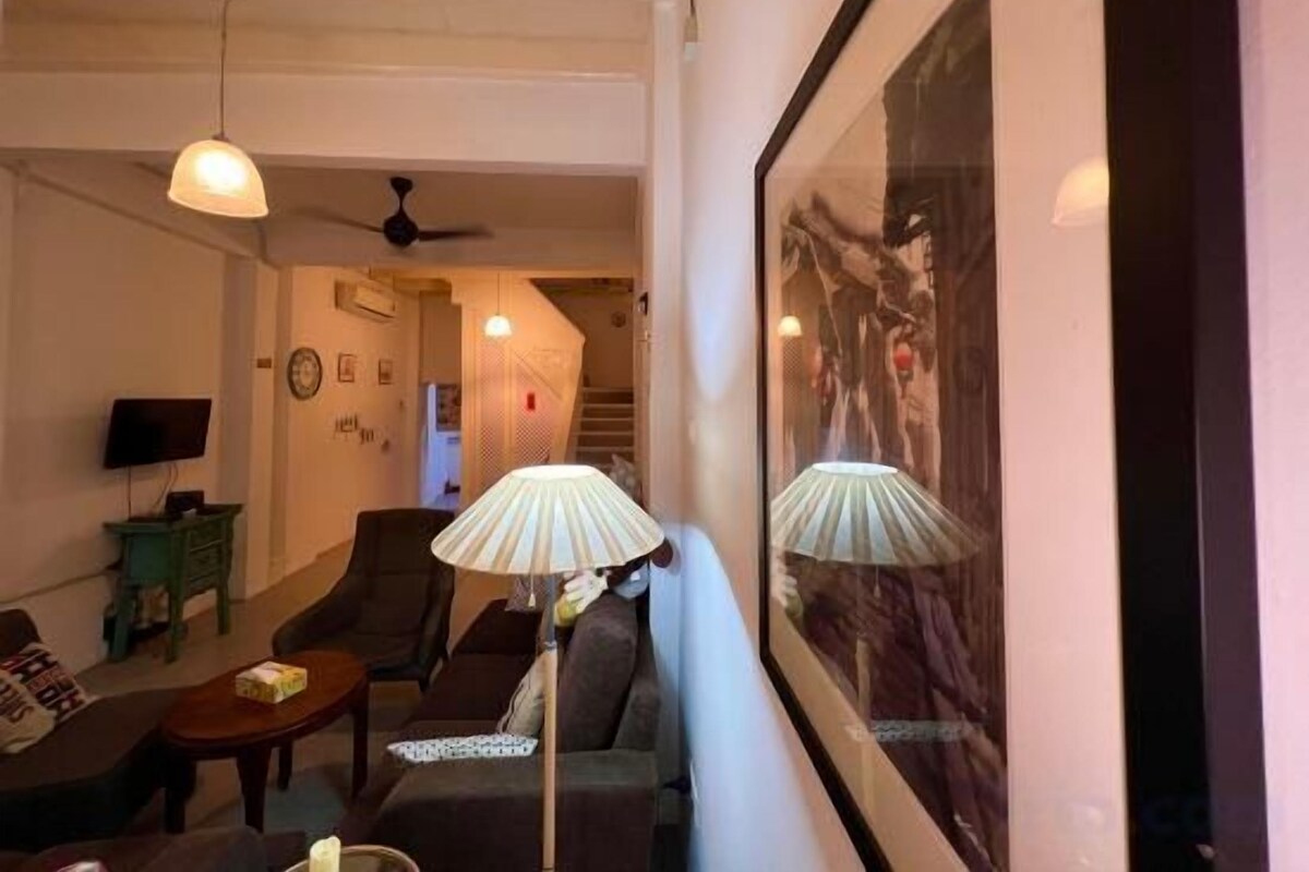 Uma sala de estar com sofá, mesa de centro, luminária e televisão.