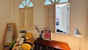 A room with two arched windows, a wooden desk with a lamp, and a mirror. - Georgetown Kyash House 23 (Northeast Penang Island)