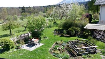 Relax in a serene garden setting surrounded by lush trees and a shaded gazebo.
