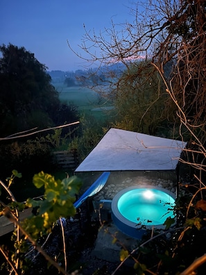 Een hottub in een tuin met uitzicht op een mistig landschap.
