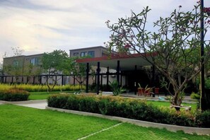 A building with a covered outdoor area, a lawn, and a tree. - Pearl Villa (Hua Hin)