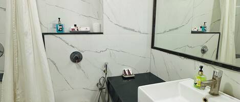 A bathroom with a white toilet, a black vanity with a white sink, a shower area, and a mirror with a picture frame.
