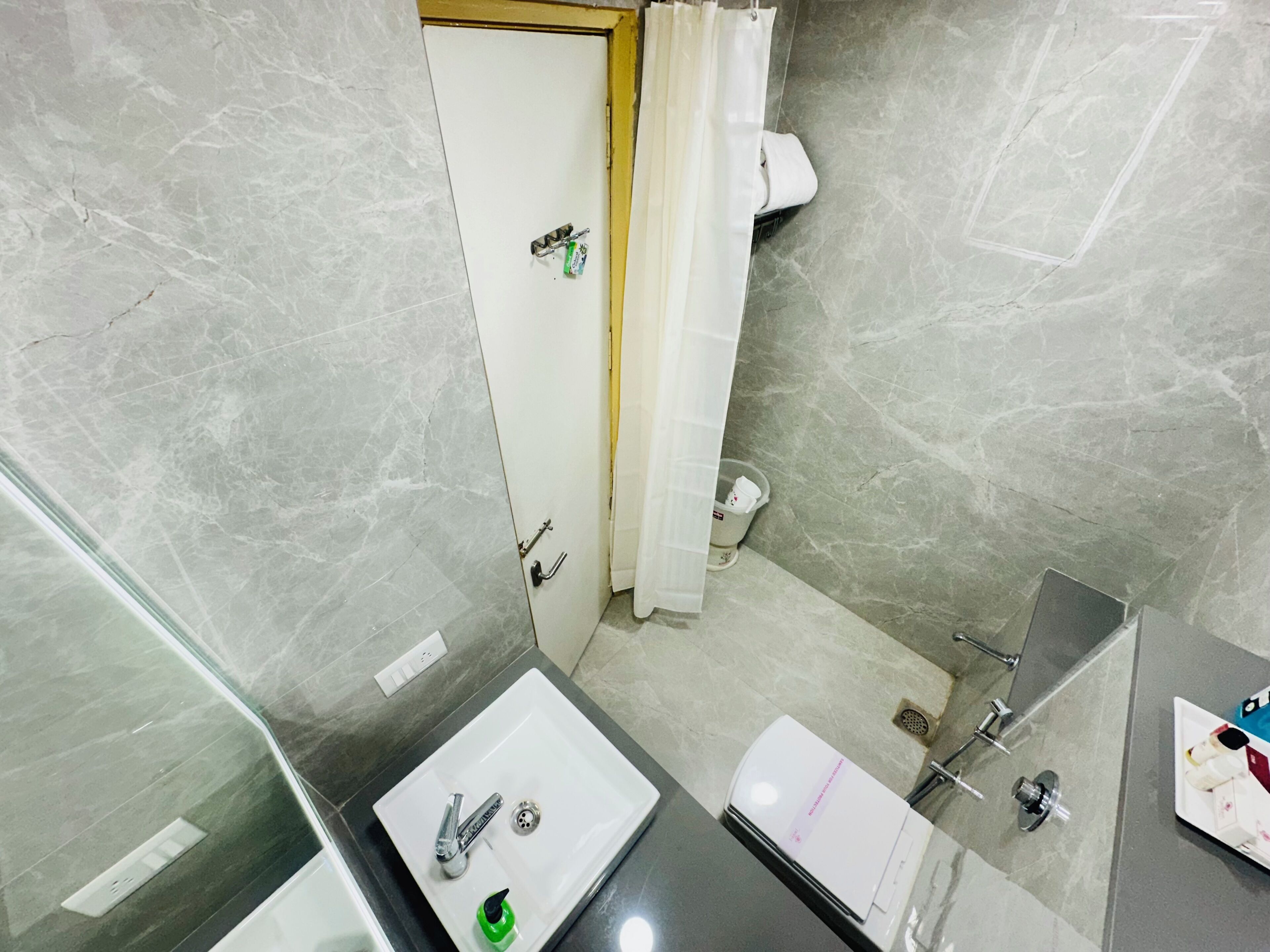 A bathroom with a white sink, a mirror, a shower, and a toilet.