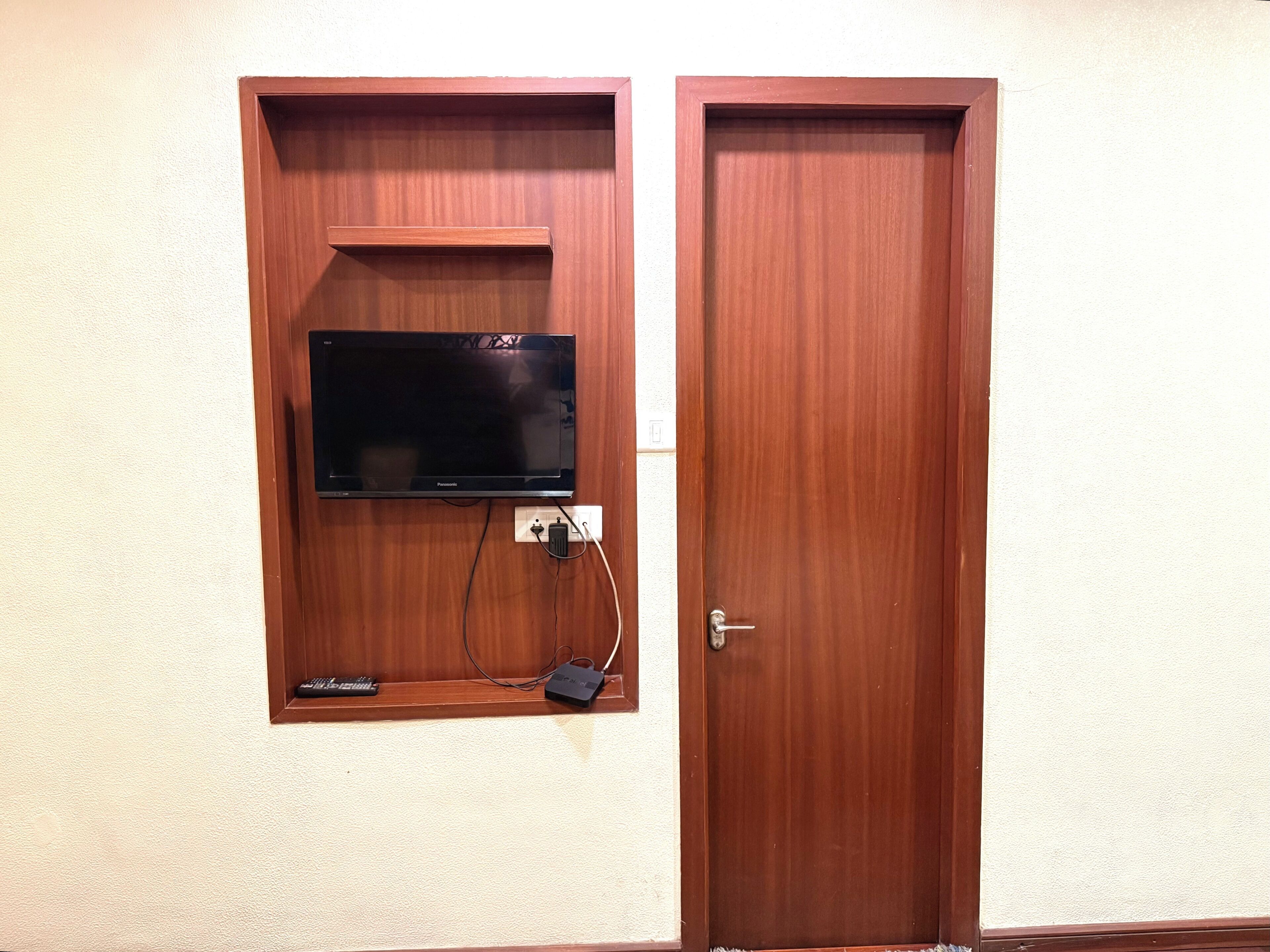 A wooden door with a mounted television and a remote control.