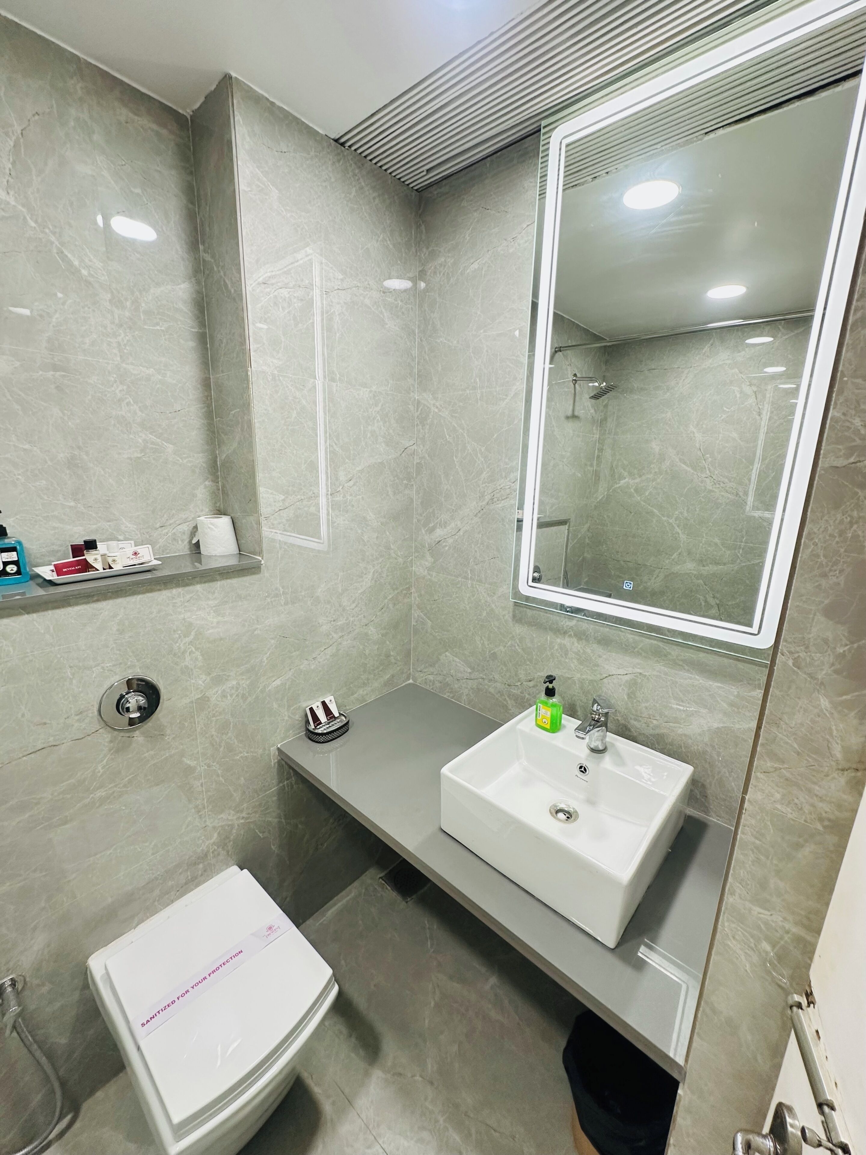 Un bagno con lavandino, specchio e water bianchi.