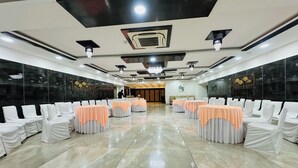 Un salón amplio con filas de mesas y sillas, un candelabro y un diseño de techo moderno.