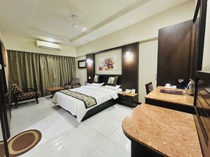 Una habitación de hotel con una cama, un escritorio, una silla, un televisor y una cortina.