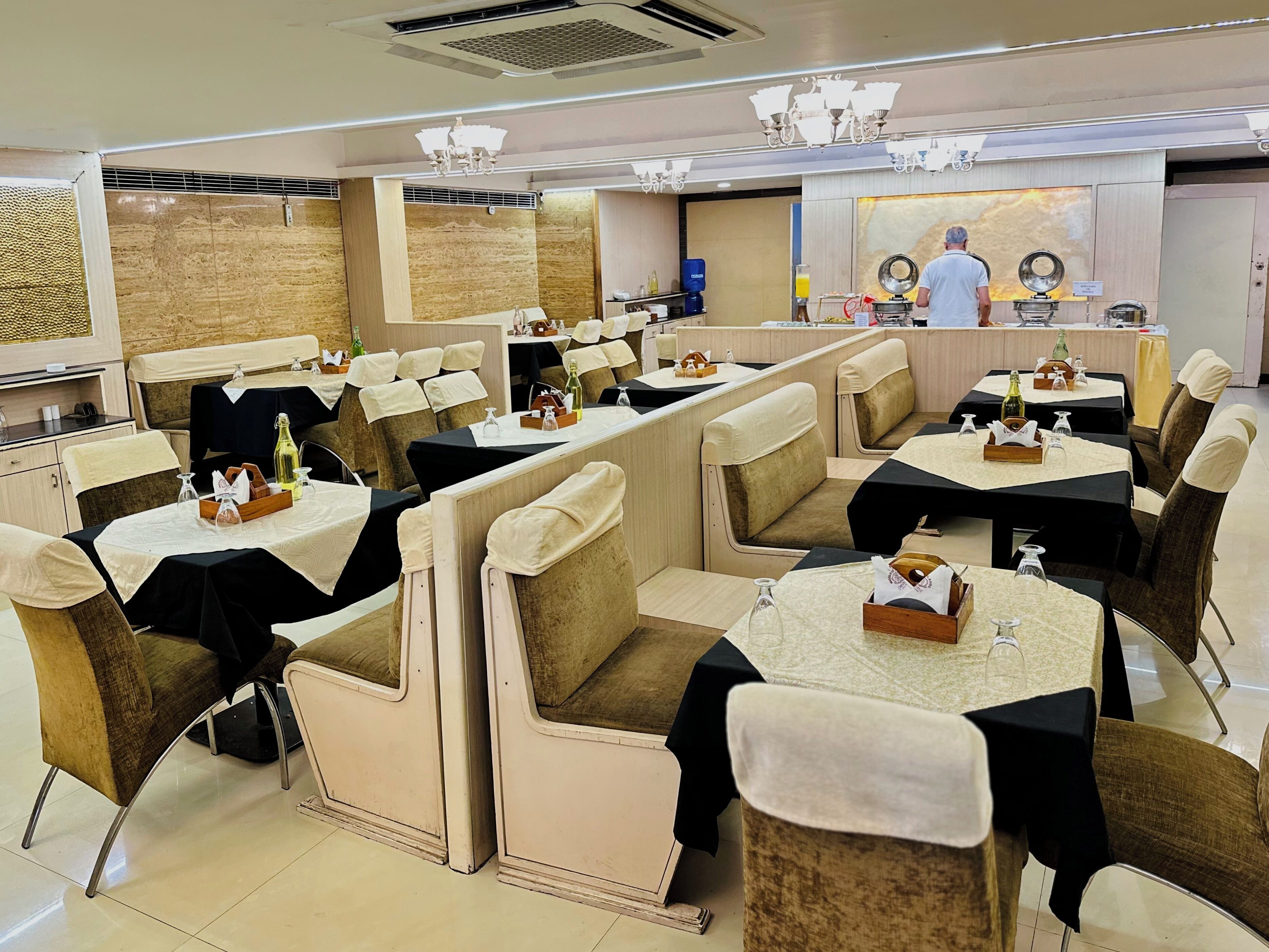 A restaurant with booth seating, tables with black tablecloths, and a bar area.