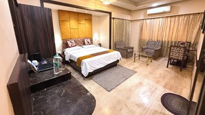 Habitación de hotel con cama, escritorio, silla, espejo y ventana con cortinas.