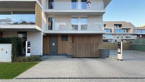 A modern multi-story building with a flat roof, large windows, and a wooden facade.