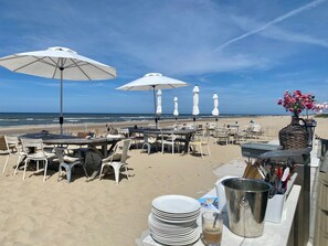 A beachside restaurant with outdoor seating, white umbrellas, and a view of the ocean. - Comfortable studio located just 200 meters from Bergen aan Zee beach. (Bergen aan Zee)