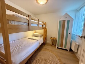 A room with bunk beds, a small round table with a plant, and a door marked with the number 17. - Comfortable studio located just 200 meters from Bergen aan Zee beach. (Bergen aan Zee)