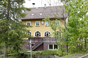 A two-story building with a sloped roof, multiple windows, and a satellite dish.