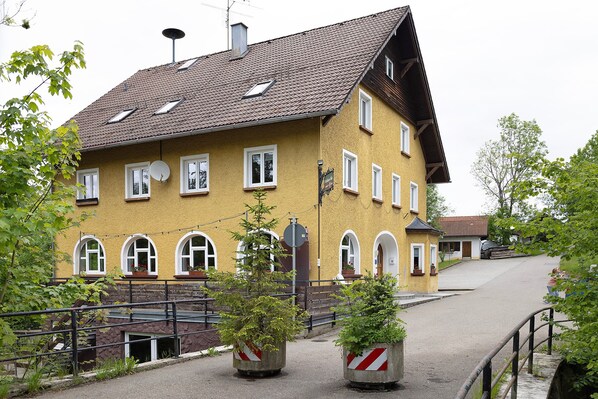 A yellow building with multiple windows, a sloped roof, and a small balcony.