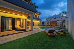Una casa moderna con piscina, mobiliario exterior y un césped bien cuidado.