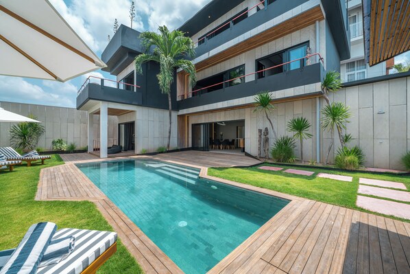 A modern two-story house with a swimming pool, outdoor furniture, and a well-maintained garden. - Villa Sunset Berawa (Canggu)