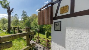 Un bâtiment blanc avec une clôture en bois, un panneau indicateur et un escalier menant à un jardin.