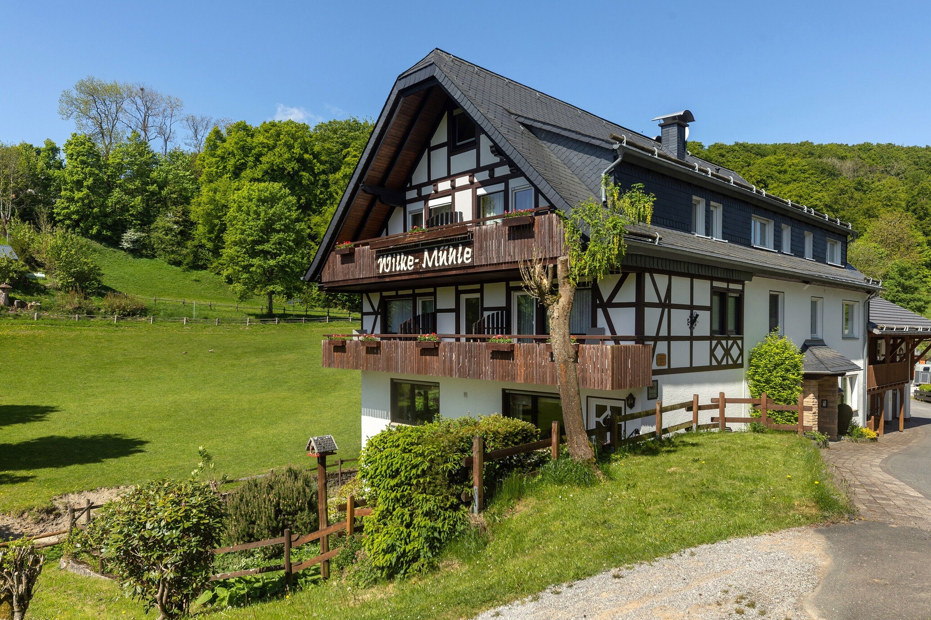 Ein traditionelles Fachwerkhäuschen mit Balkon, umgeben von einer grünen Landschaft.