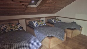 A room with three wooden beds, each with a checkered bedspread and matching pillows.