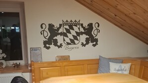 A dining area with a wooden table and chairs, a wall-mounted coat rack, and a coat hanging on it.