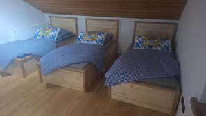 A room with three wooden beds, each with a checkered bedspread and matching pillows. - Apartment 'Wohnung Aussicht' with Wi-Fi (Wald)