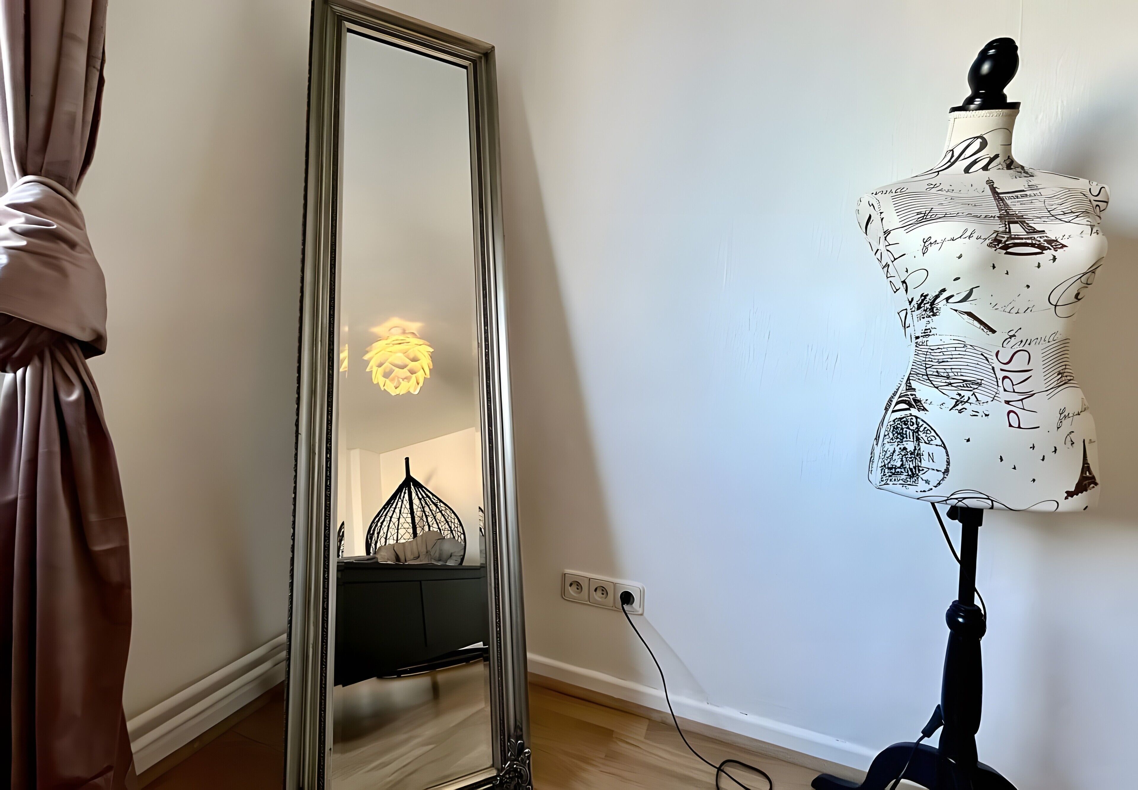 Ein Zimmer mit einem Spiegel, der eine Lampe, eine Verkaufsattitüte und eine Kommode reflektiert.
