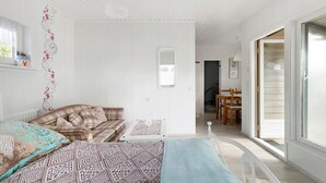 Een slaapkamer met een bed, twee nachtkastjes, een raam en een deur naar een eetgedeelte.