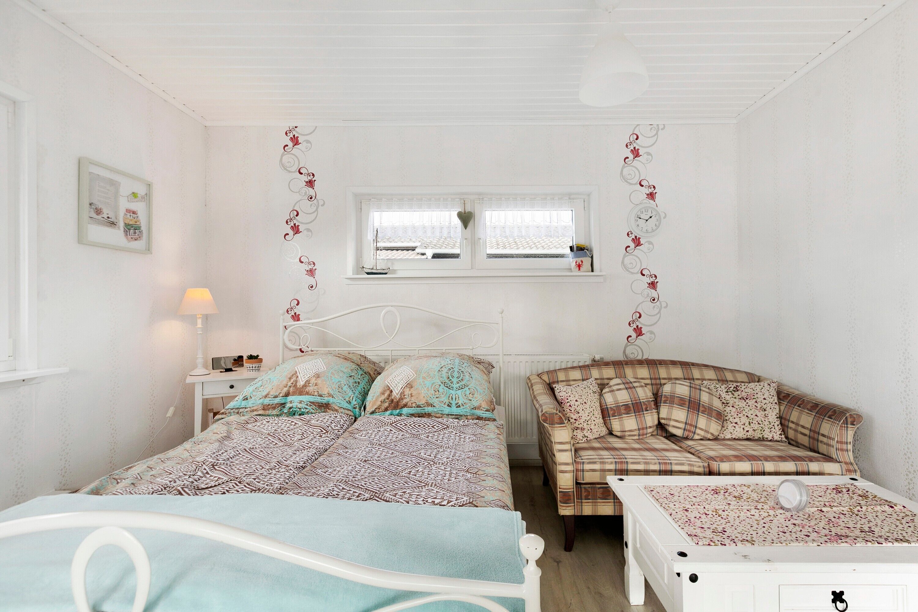Een slaapkamer met een bed, een slaapbank, een raam en een nachtkastje.