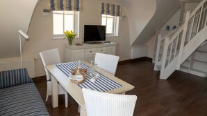 Un comedor con mesa, sillas, televisor y escalera.