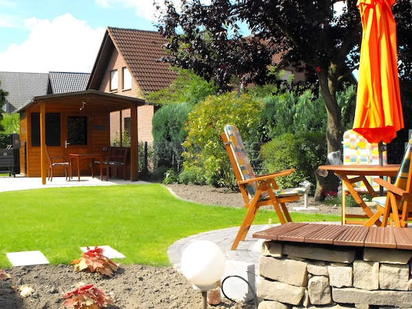 A wooden house with a patio, outdoor seating, and a stone wall.